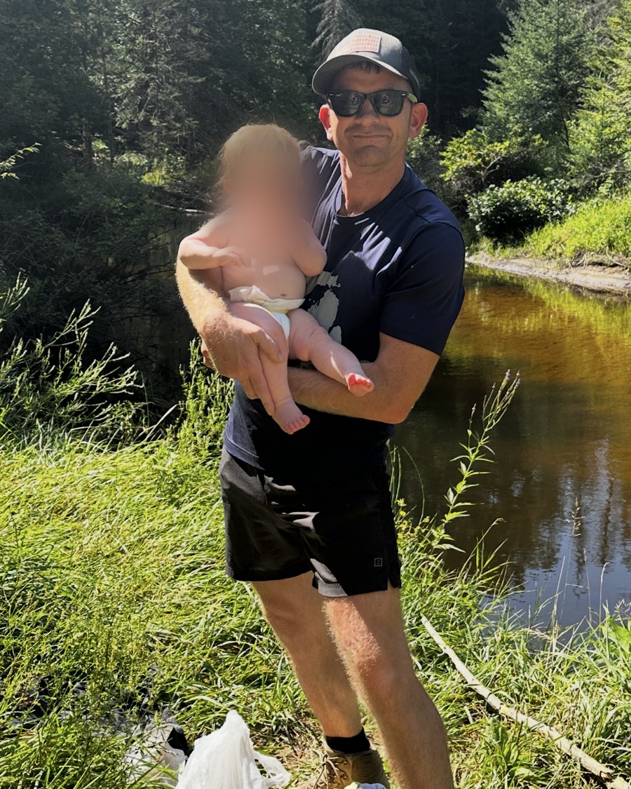 Andrew Jernigan, founder of Peninsulas AI, outdoors holding his child by a river